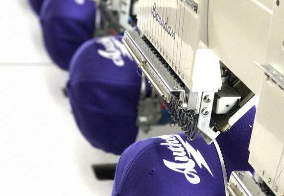 image of hats being embroidered with a custom logo in-house by our team